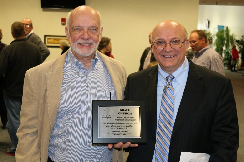 Pastor Phil Winfield (right) and Pastor Paul Dykstra (left) holding a plague from Metro Baptist Association that states: "Praise God for your 35 years of faithfulness." and quotes I Corinthians 4:2: "It is required of stewards that they be found faithful."