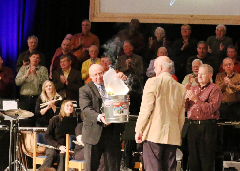 Pastor Phil Winfield (L) burns the mortgage note while Pastor Paul Dykstra looks on approvingly. 