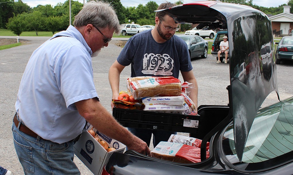 Doug Mitchell (left), pastor of Midland Baptist Church in rural Tennessee, and Roger Brown of Cedar Grove United Methodist Church, load food into the car of a family receiving aid at Midland's Journey of Hope Ministry Center. Photo by Lonnie Wilkey